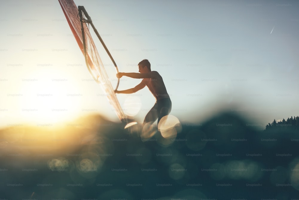 Vue en contre-plongée de la silhouette d’un surfeur en équilibre sur une planche à voile. Planche à voile naviguer sur la planche à voile.