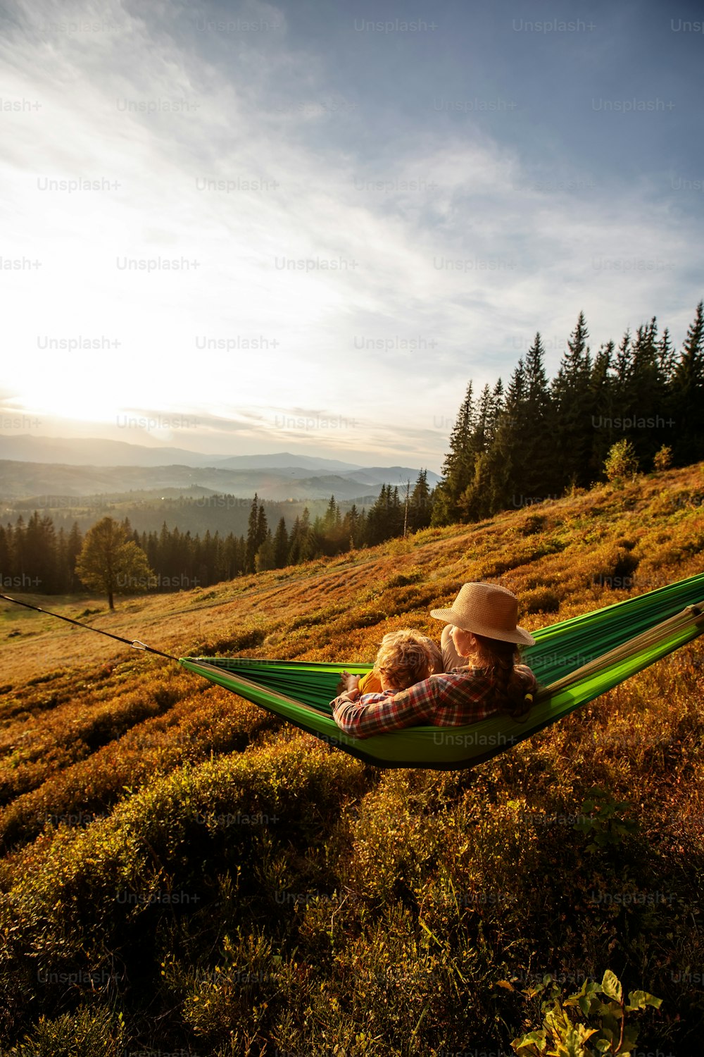 Niño turista descansando en una hamaca en las montañas al atardecer