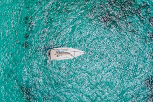 White yacht in a lagoon with azure shiny water, aerial top view