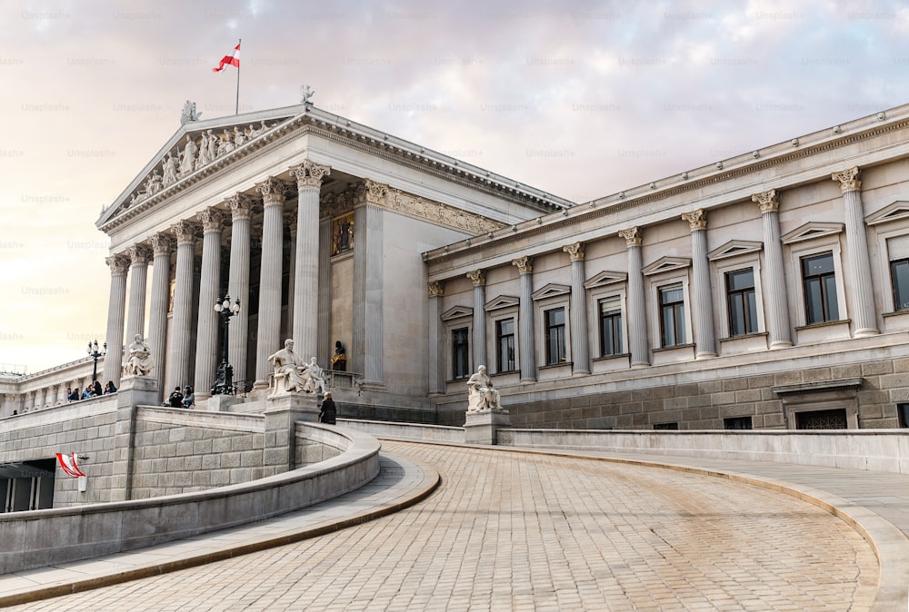 그리스 스타일의 오스트리아 국회 의사당 정문에는 철학자 동상과 유명한 팔라스 아테나 분수가 있는 흰색 기둥이 있으며 비엔나에 있습니다.