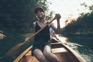 Donna che rema in canoa su un lago forestale, copia spazio.
