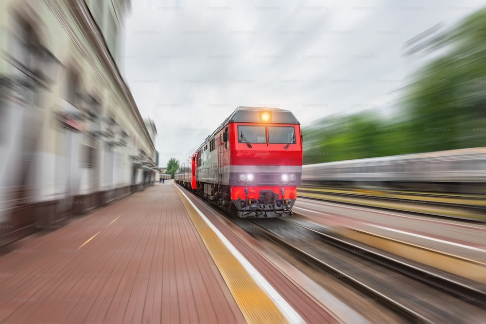 Una locomotora diésel con un tren de pasajeros con un vagón corre a lo largo de la vía férrea