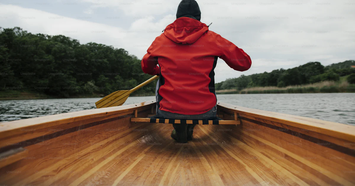 Rear view of man paddling canoe on the lake. Rainy day boat ride. photo ...