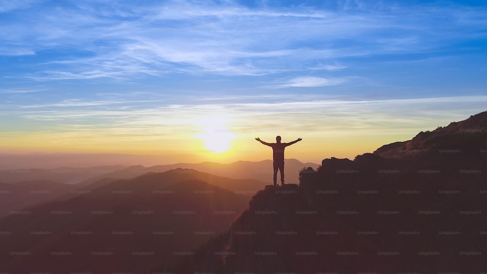 The man standing on the mountain on the picturesque sunset background