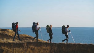 The four travelers with backpacks walking to the sea shore