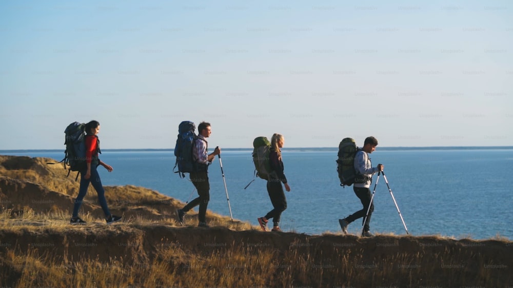 The four travelers with backpacks walking to the sea shore