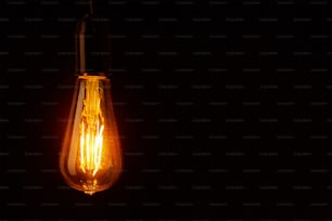 Vintage light bulb on black background with copy space. Glowing edison bulb