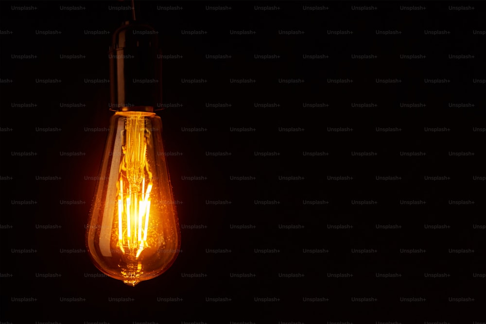 Vintage-Glühbirne auf schwarzem Hintergrund mit Kopierplatz. Glühende Edison-Glühbirne