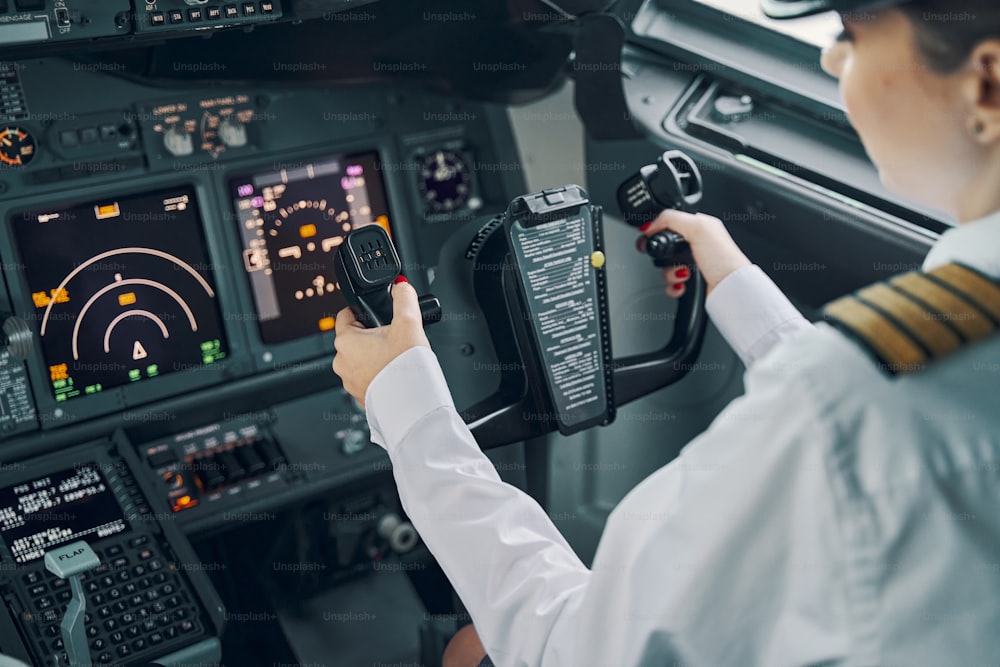 Back view of a woman first officer sitting at the control column in the flight deck