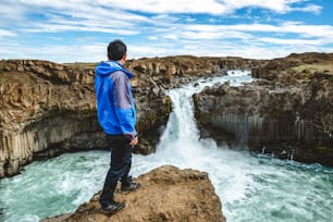Traveler hiking in Icelandic summer landscape at the Aldeyjarfoss waterfall in north Iceland. The waterfall is situated in the northern part of the Sprengisandur Road within the Highlands of Iceland.