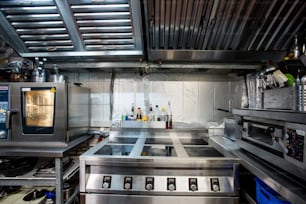 コンテンポラリーレストランの大型キッチンのインテリアの一部には、食品を焼いたり焙煎したりするための電気ストーブやオーブン、台所用品などがあります