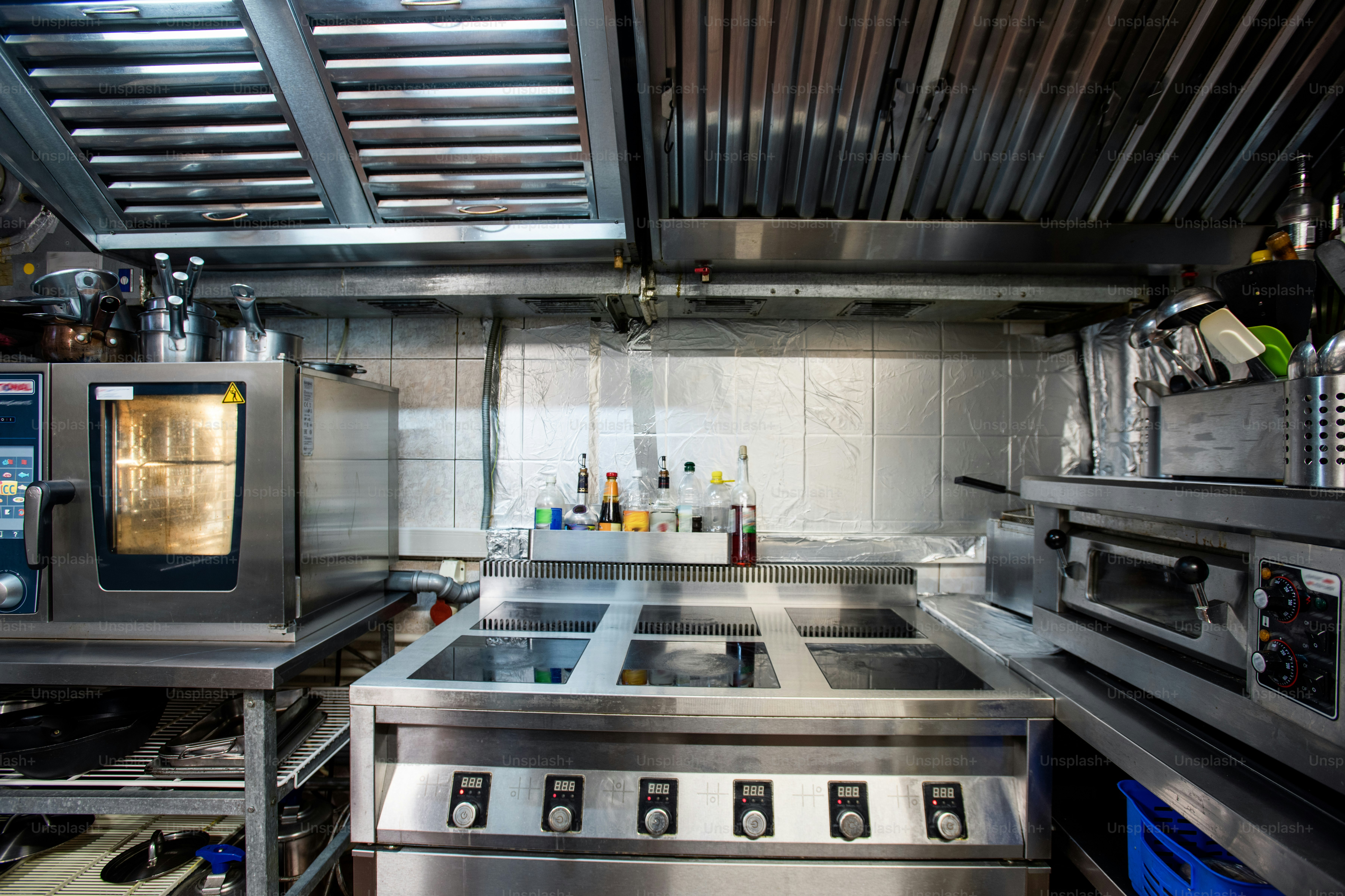 Part of interior of large kitchen of contemporary restaurant including electric stove and oven for baking and roasting food, kitchenware