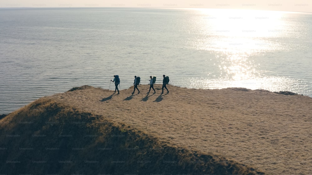 Las cuatro personas con mochilas paradas en la orilla del mar