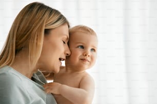 Young mother holding her baby with affection at home.