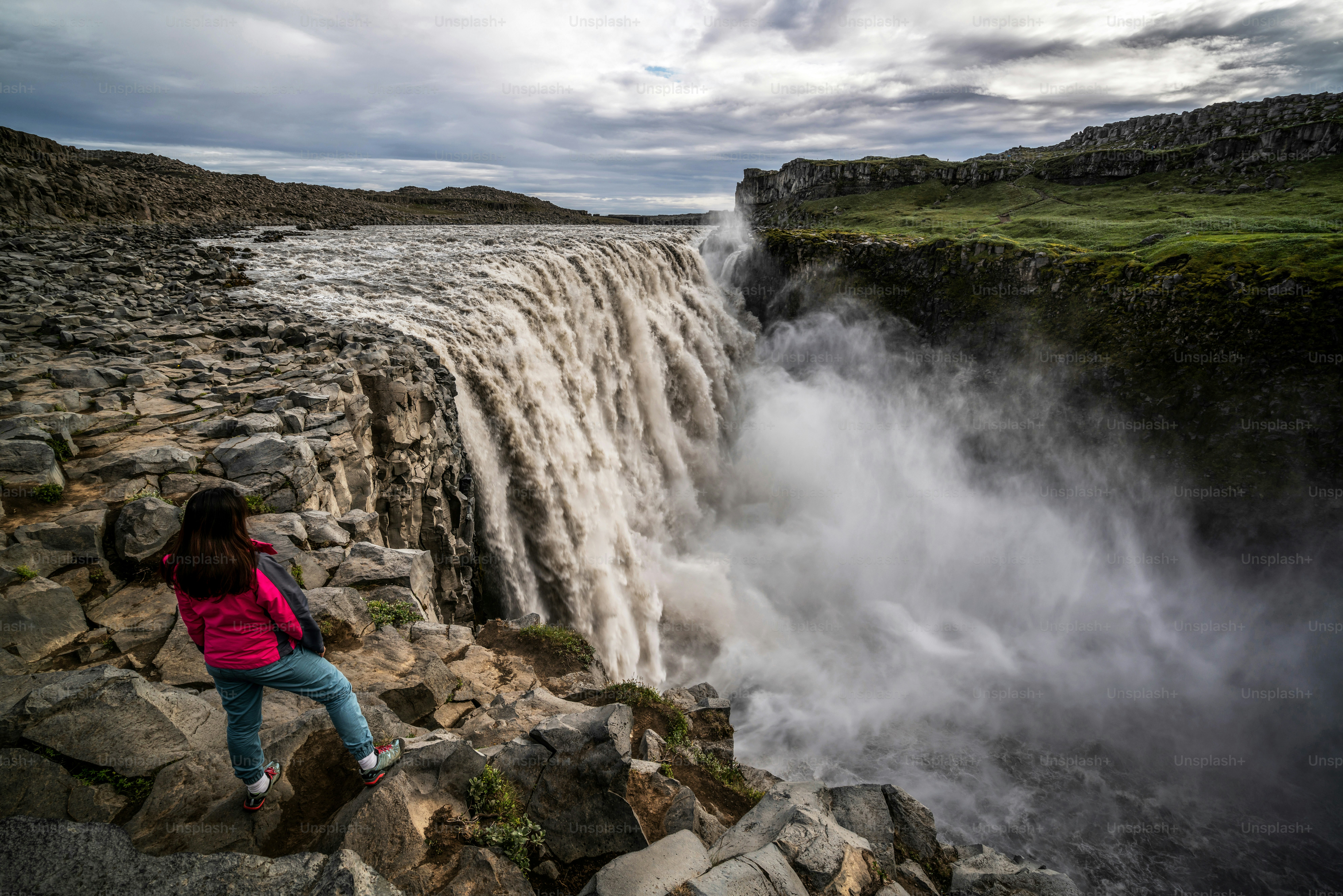 Femme voyageuse dans le magnifique paysage islandais de la cascade de Dettifoss dans le nord-est de l’Islande. Dettifoss est une cascade du parc national de Vatnajokull réputée pour être la cascade la plus puissante d’Europe.