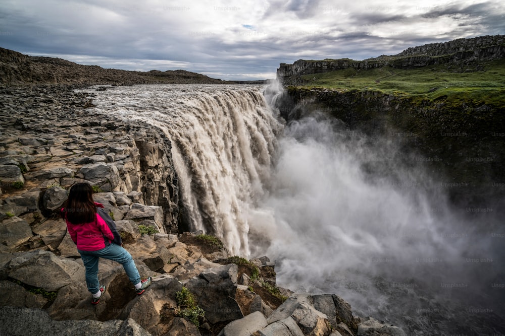 Mujer viajera en el increíble paisaje islandés de la cascada de Dettifoss en el noreste de Islandia. Dettifoss es una cascada en el Parque Nacional de Vatnajökull que tiene fama de ser la cascada más poderosa de Europa.