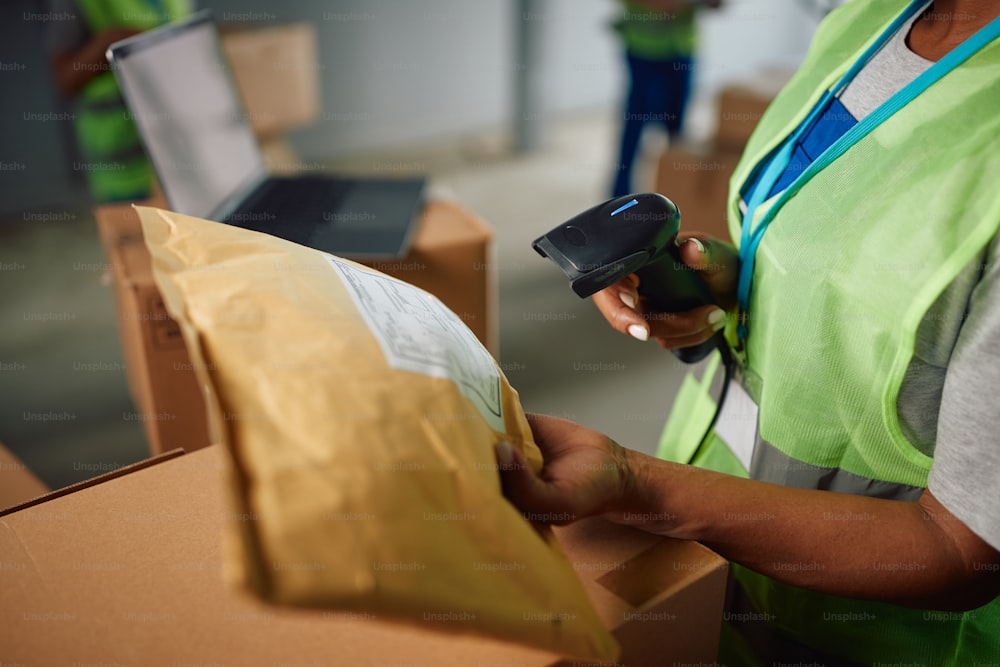Primer plano del trabajador del almacén escaneando la etiqueta de los paquetes en el compartimento de distribución.