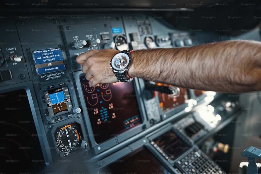 Close up photo of unrecognized pilot touching the buttons and switches on the control panel