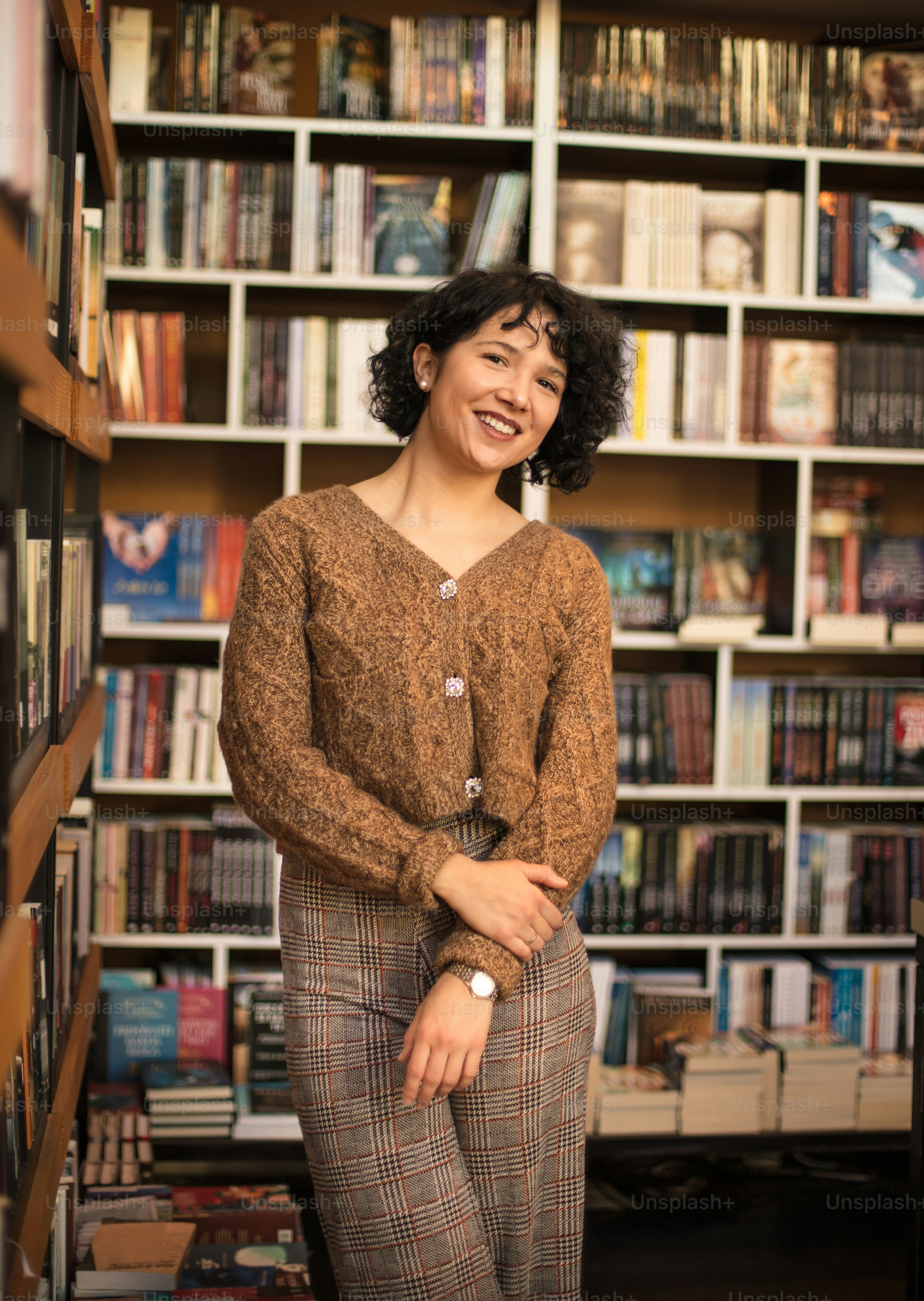 Mujer feliz de pie en la biblioteca y mirando a la cámara.