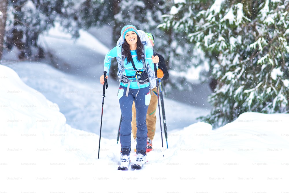눈이 내리는 동안 숲에서 스키 투어. 행복한 소녀