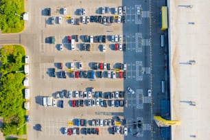 Aerial top down view of the parking lot with many cars of supermarket shoppers in the city grocery store