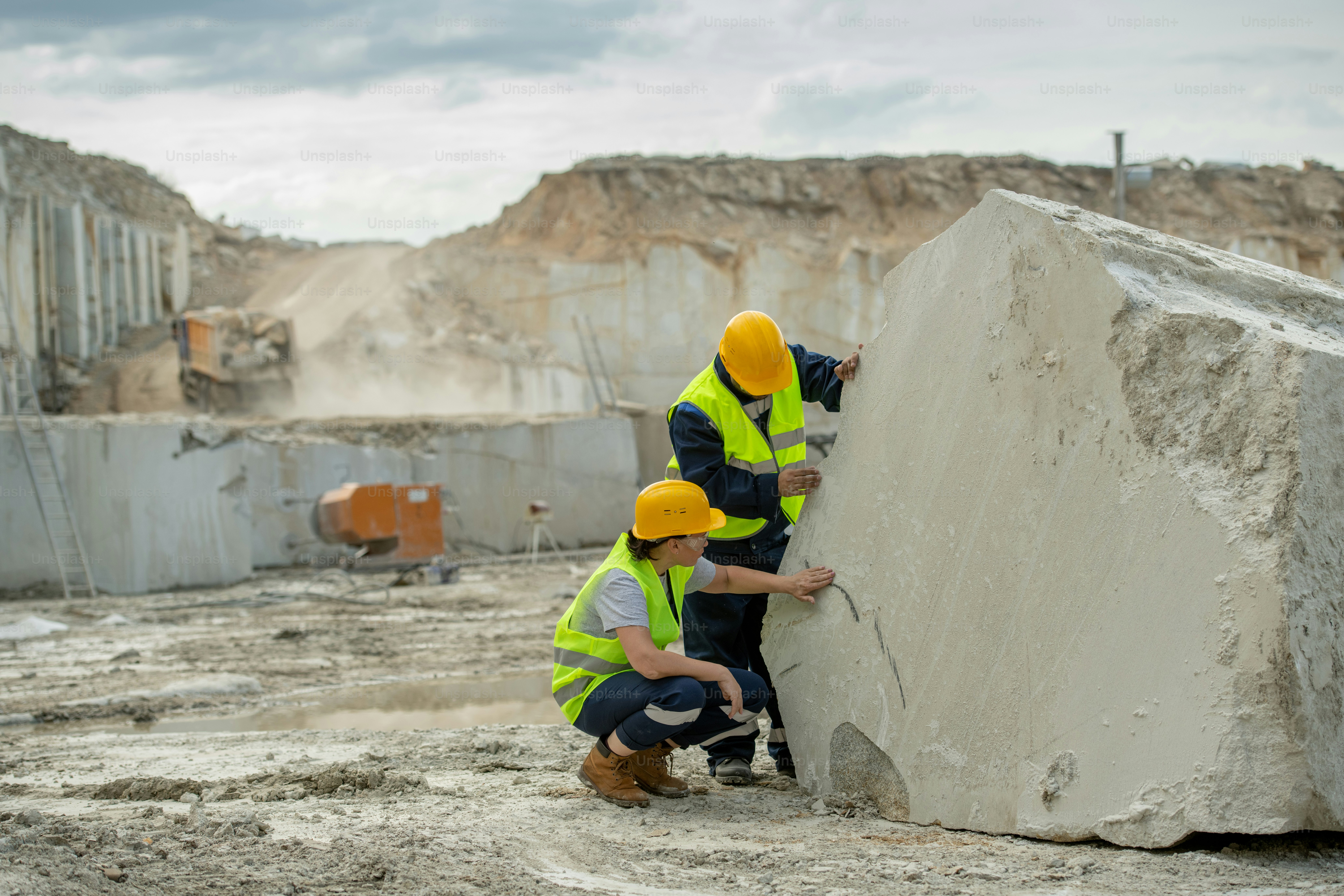 Zwei junge Baumeister in Schutzhelmen und Uniform arbeiten an riesigen Betonstücken