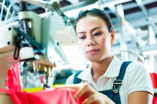 Seamstress or worker in a factory sewing with a industrial sewing machine, she is very accurate