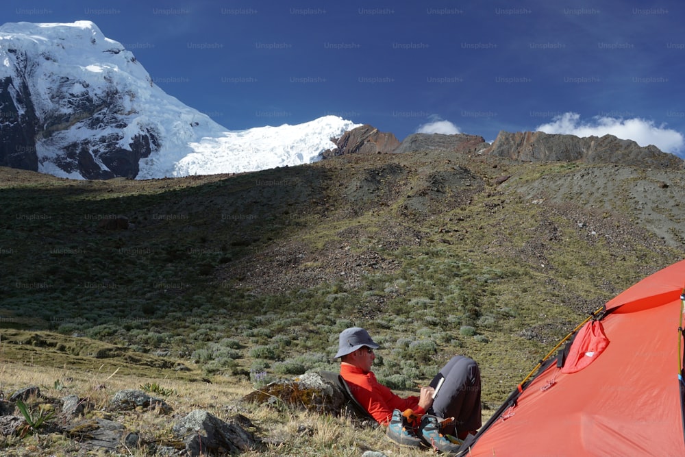 ペルーのコルディリェラ・ブランカでテントの外に座り、日記を書く登山家