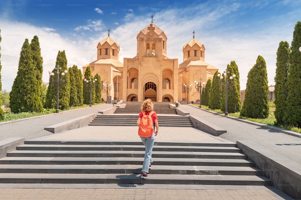 Passeios turísticos e turismo em Yerevan. Viajante do sexo feminino com mochila sobe as escadas que levam à entrada da Catedral de São Gregório O Iluminador.