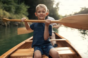 Ragazzo che impara a pagaiare in canoa con suo padre in una bella giornata di sole.