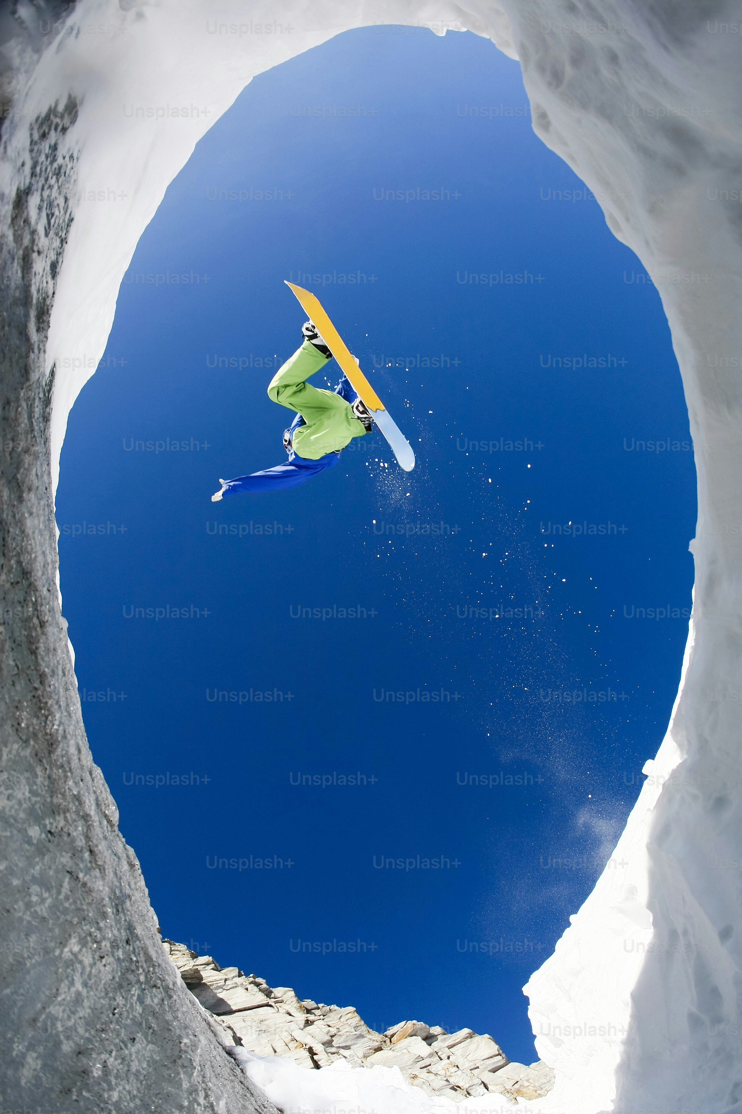 View from below of excited snowboarder leaping over mountainside and taking pleasure in it     Note to inspector: the image is pre-Sept 1 2009