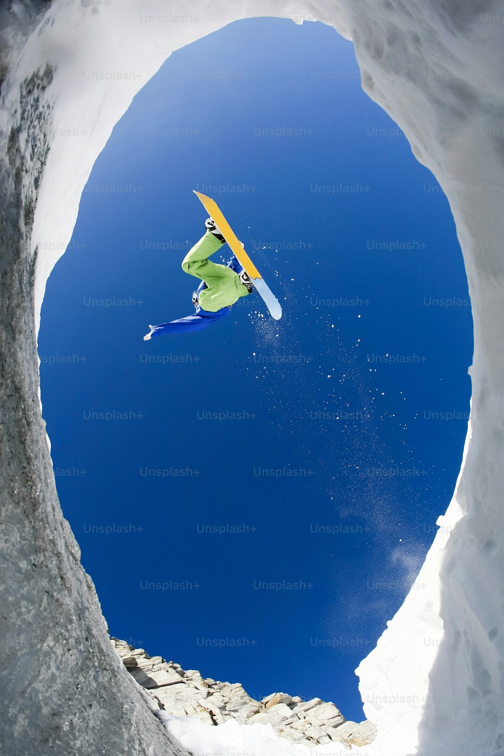Blick von unten auf einen aufgeregten Snowboarder, der über den Berghang springt und sich daran erfreut Hinweis für den Inspektor: Das Bild ist vor dem 1. September 2009