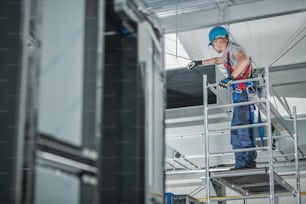 大型商業ビルの天井に新しく設置された換気シャフトをチェックする建設作業員。
