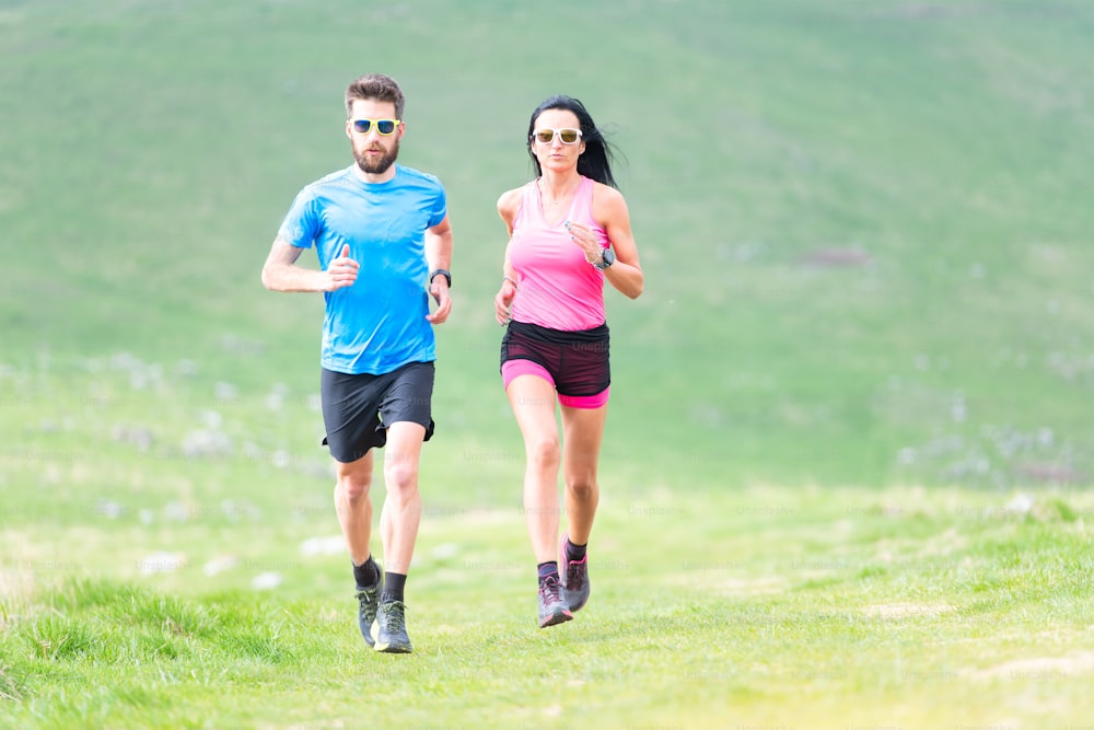 Action of runners in hilly meadows in the summer. Man and woman
