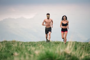 Sporty man and woman run hot in the summer on hill meadows