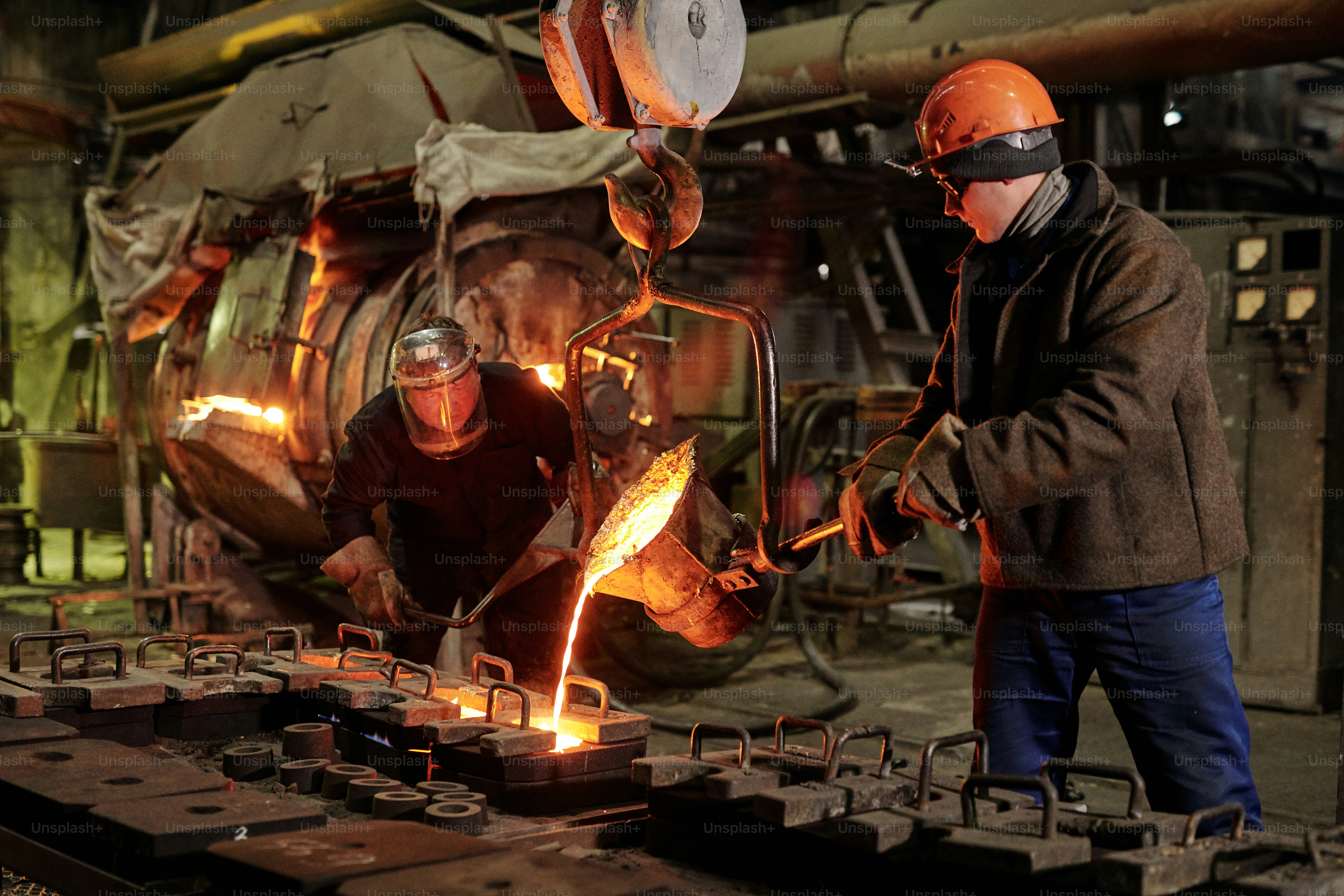 Workers in helmets working in team they melting iron in metal factory