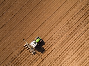 Foto aérea de um agricultor semeando, semeando colheitas no campo. A semeadura é o processo de plantio de sementes no solo como parte das atividades agrícolas do início da primavera.