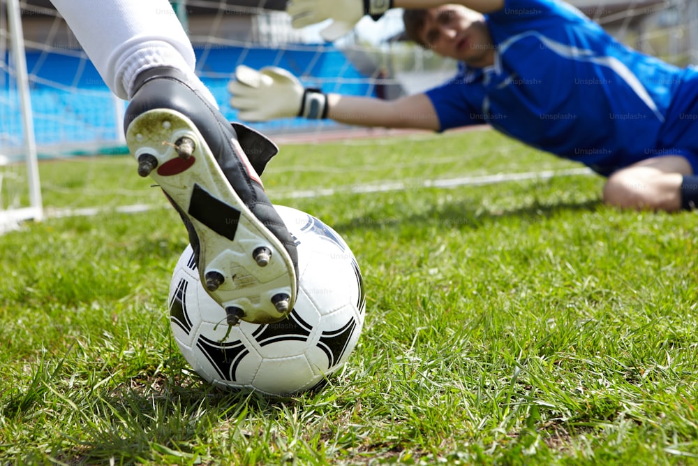 Horizontales Bild eines Fußballs mit Fuß des Spielers, der ihn tritt