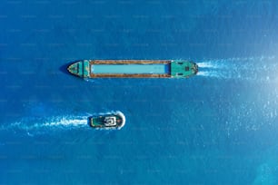 Cargo ship barge and tugboat sail to meet each other in the seaport of the port, aerial view