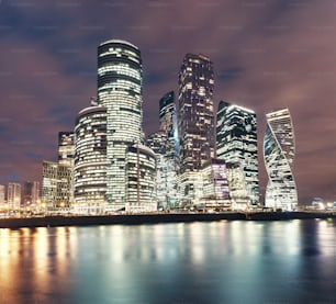 モスクワ市の超高層ビルや国際ビジネスセンターを夜間にライトで照らし、水池の堤防からの眺めを反射