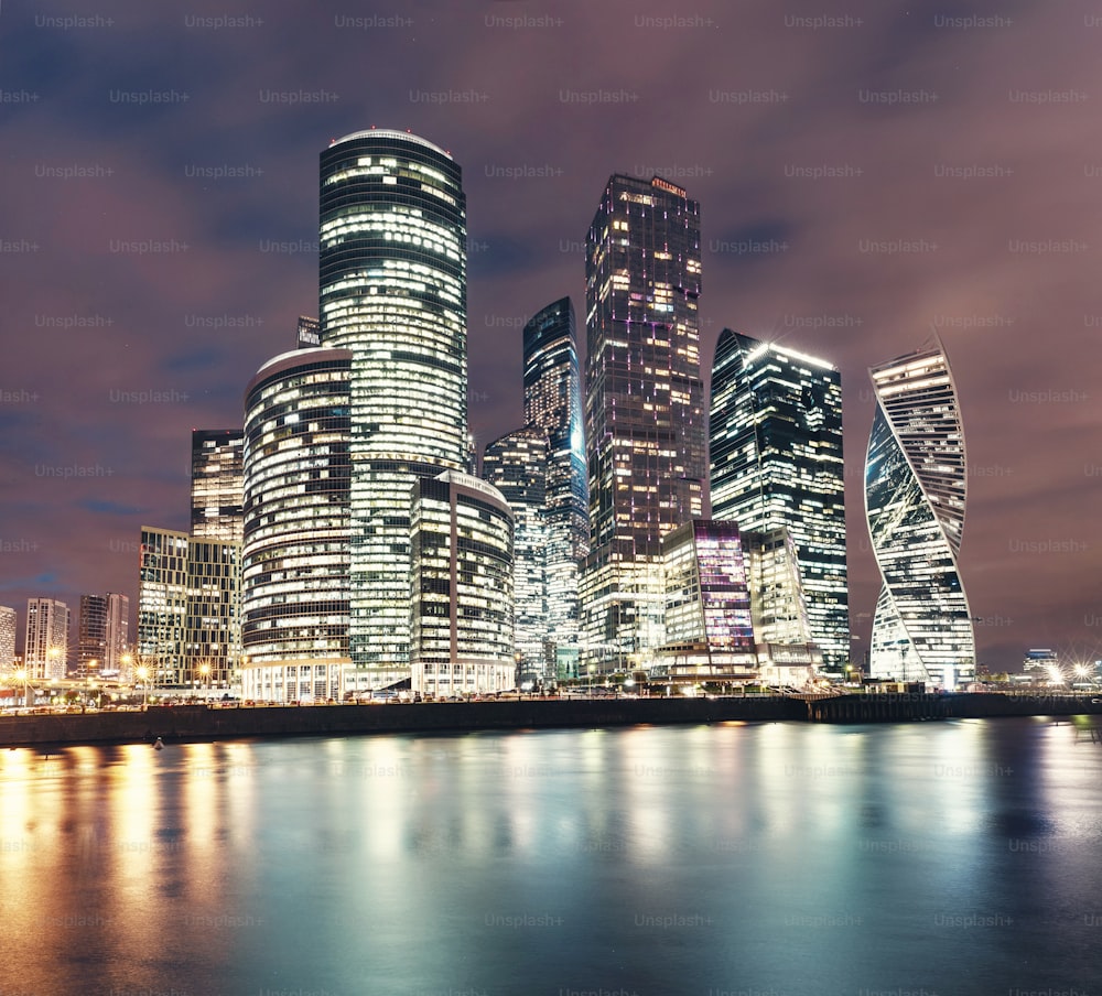 モスクワ市の超高層ビルや国際ビジネスセンターを夜間にライトで照らし、水池の堤防からの眺めを反射