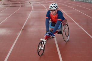 Future Paralympic champion. Paraplegic male athlete sitting in specialized sport wheelchair and warming up on track before race