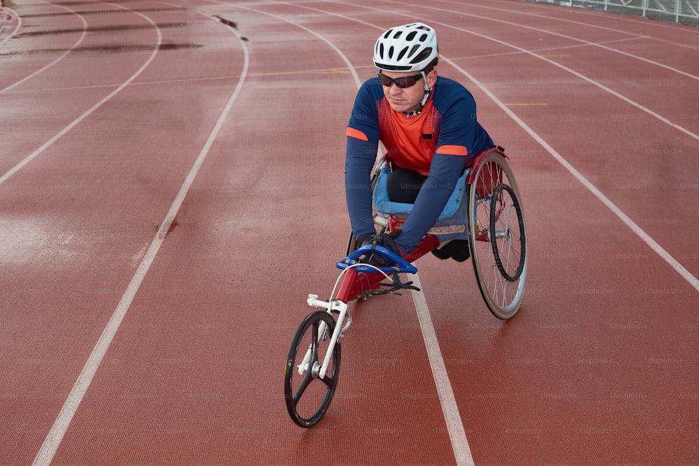 Futuro campeão paralímpico. Atleta paraplégico do sexo masculino sentado em cadeira de rodas esportiva especializada e aquecendo-se na pista antes da corrida