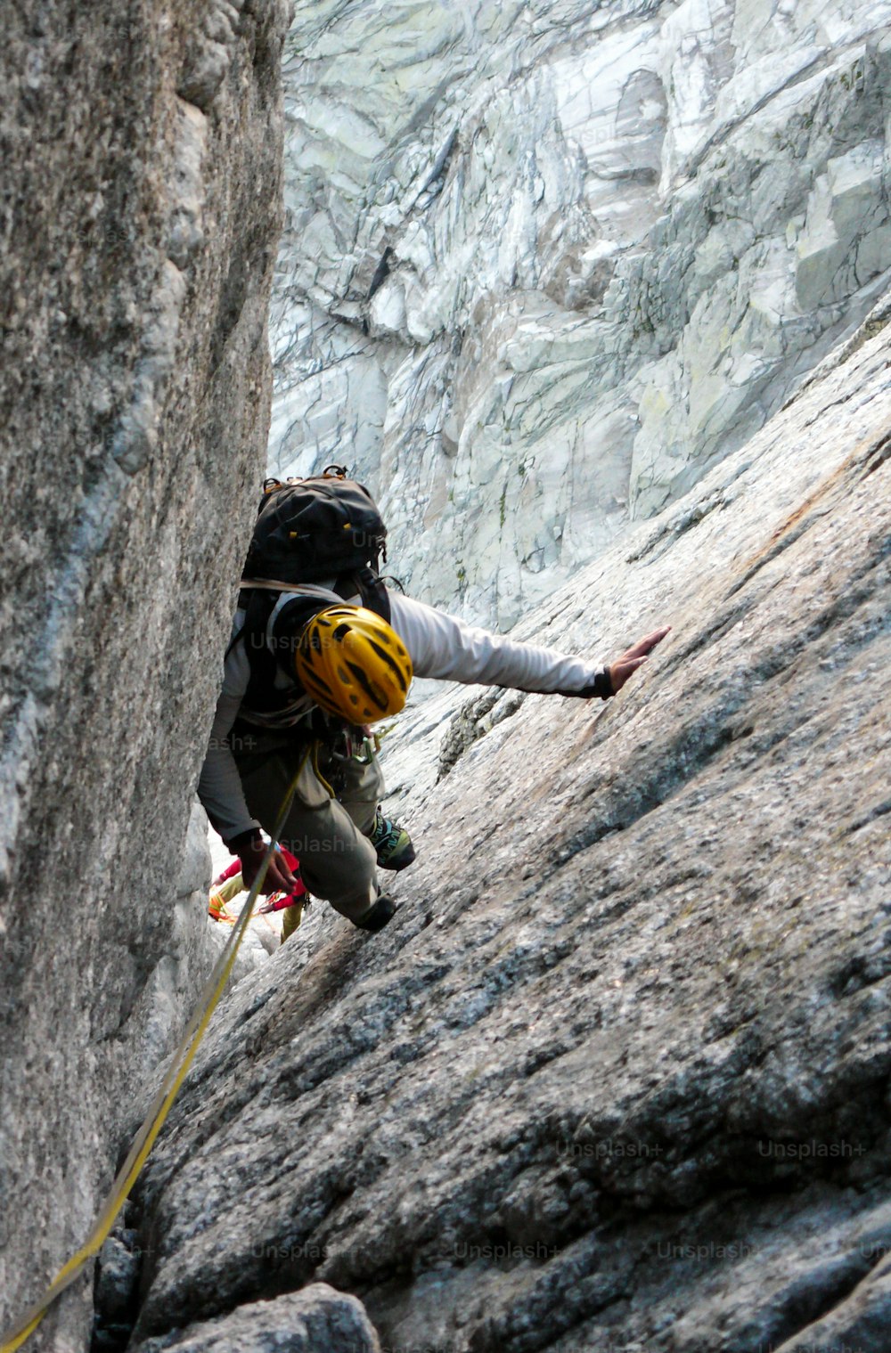 Escalador de montaña masculino en una difícil chimenea de granito de una ruta clásica en los Alpes suizos