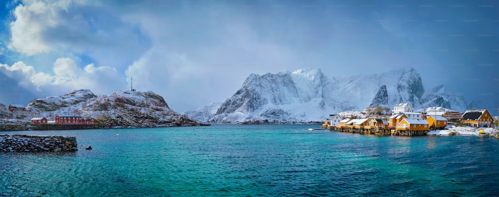 겨울에 눈이 내리는 Sakrisoy 어촌 마을의 노란색 rorbu 주택의 파노라마. 로포텐 섬, 노르웨이