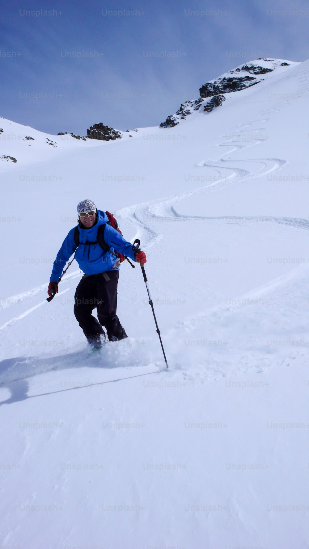 male skier and fresh tracks in untouched powder snow in the backcountry of the Swiss Alps near St. Moritz