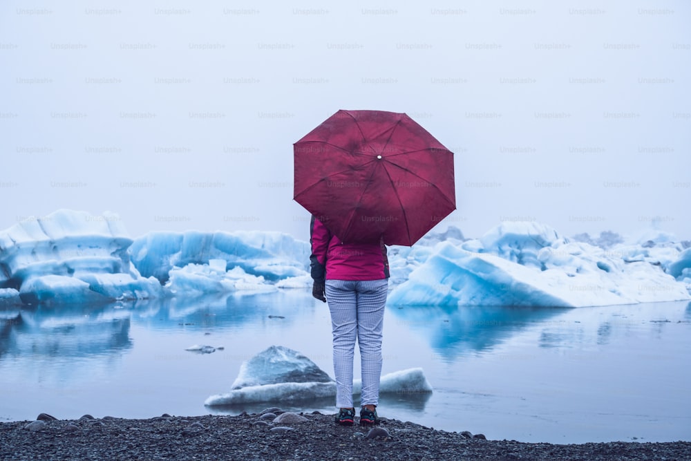 여성 여행자가 아이슬란드의 아름다운 빙하 석호인 요쿨살론으로 여행을 떠납니다. 요쿨살론은 유럽 아이슬란드 남동부의 바트나요쿨 국립공원에 있는 유명한 여행지입니다. 추운 겨울 얼음 자연.