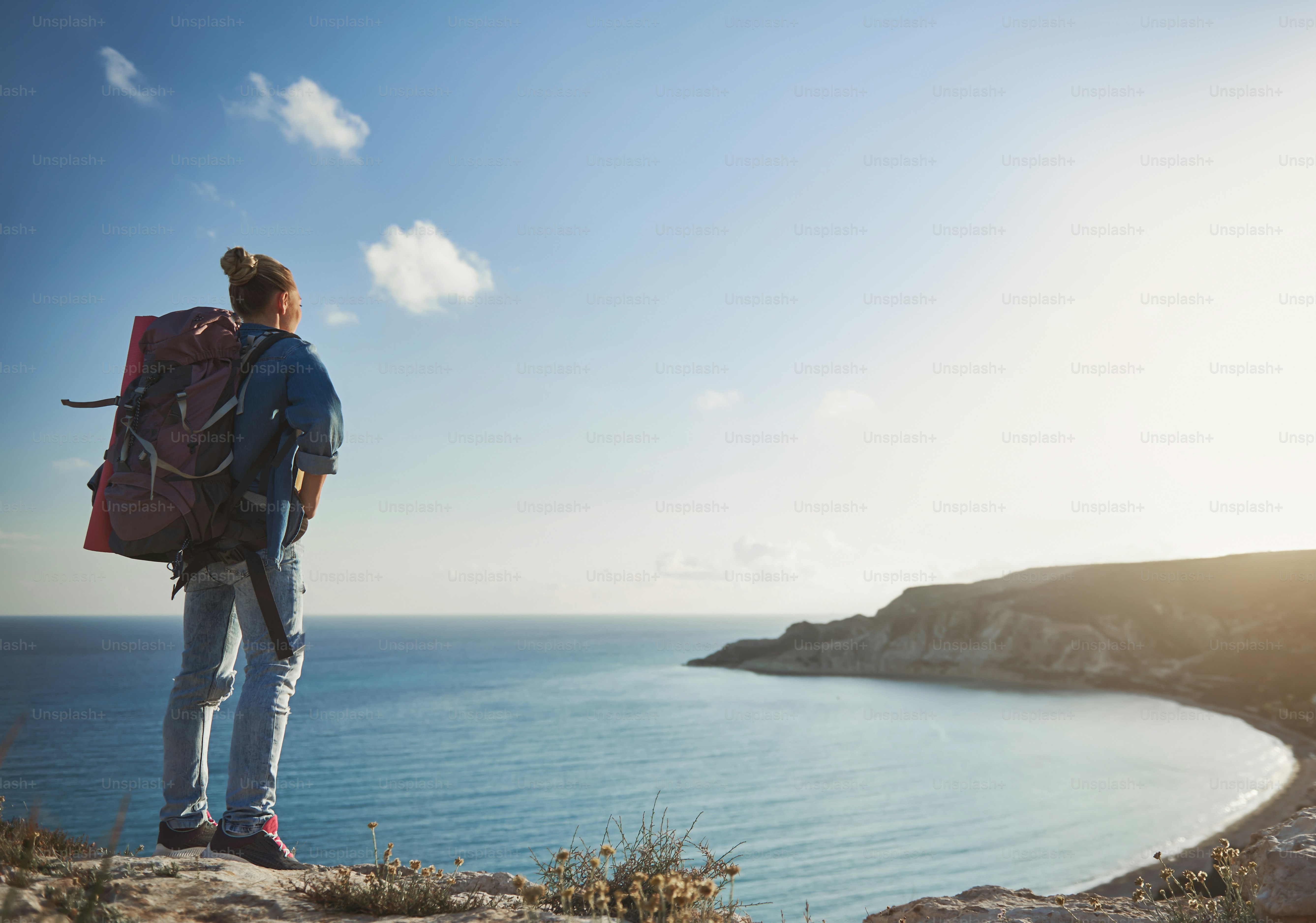 Girl being in camping trip. She is standing with her back on mountain and eyeing beautiful shoreline