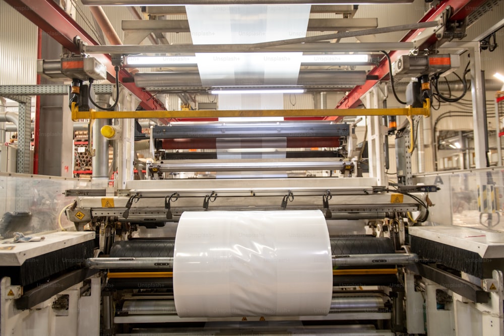 Huge industrial machine with large rolled newly produced transparent polyethylene film in factory workshop