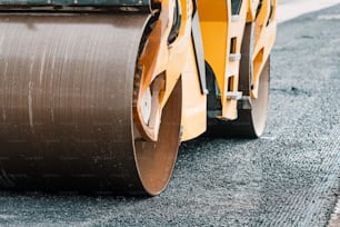 The roller paver levels the asphalt during the construction of the highway road